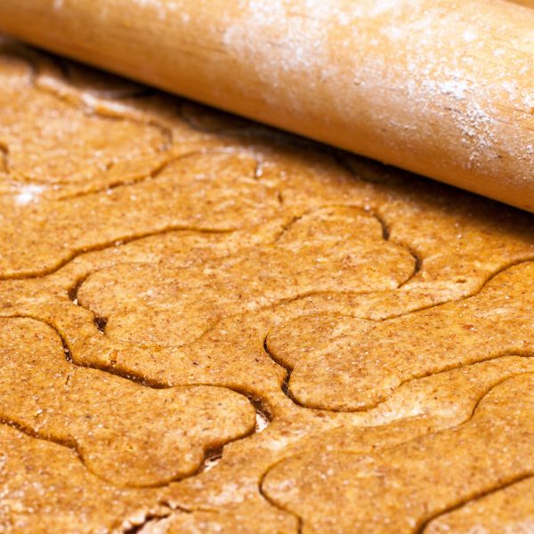 DIY dog treat recipes - rolling out dough with bone-shaped treat cutouts